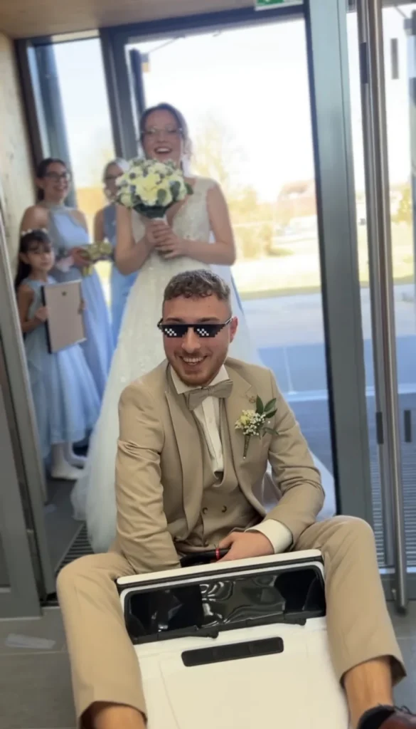 Bräutigam mit Sonnenbrille auf einem Mini-Fahrzeug vor der Braut
