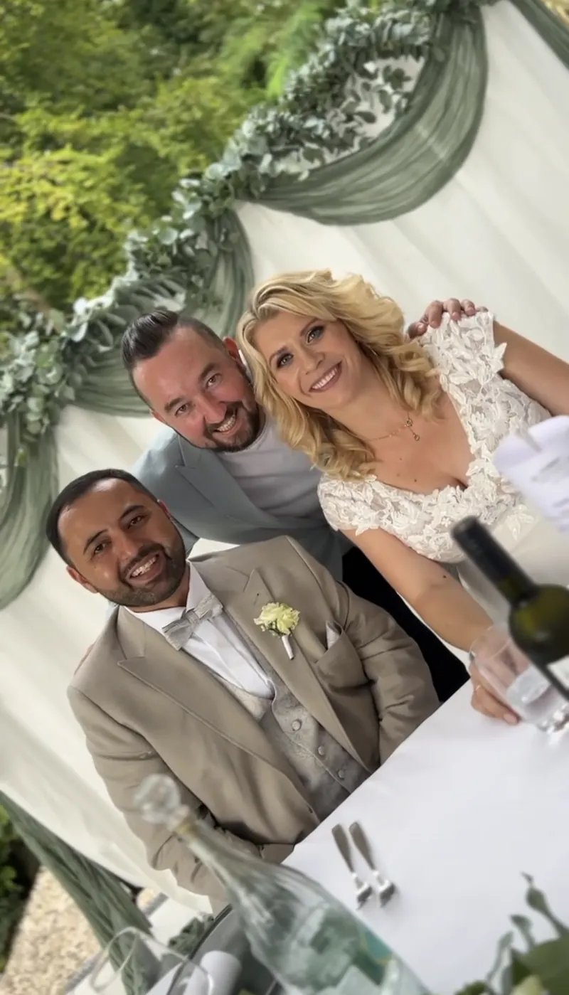 Lachendes Brautpaar am Hochzeitstisch mit Tamada Andrey Singer Lachendes Brautpaar am Hochzeitstisch mit Tamada Andrey Singer