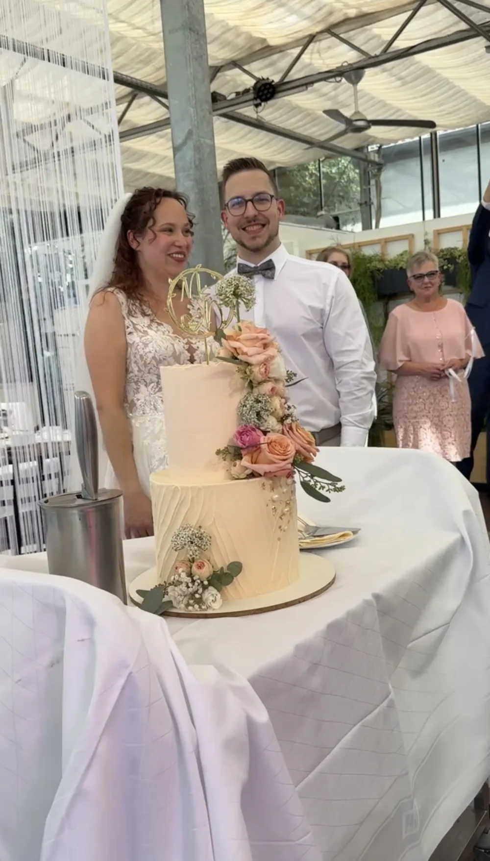 Brautpaar steht hinter der Hochzeitstorte in einer Location mit Glasdach Brautpaar steht hinter der Hochzeitstorte in einer Location mit Glasdach