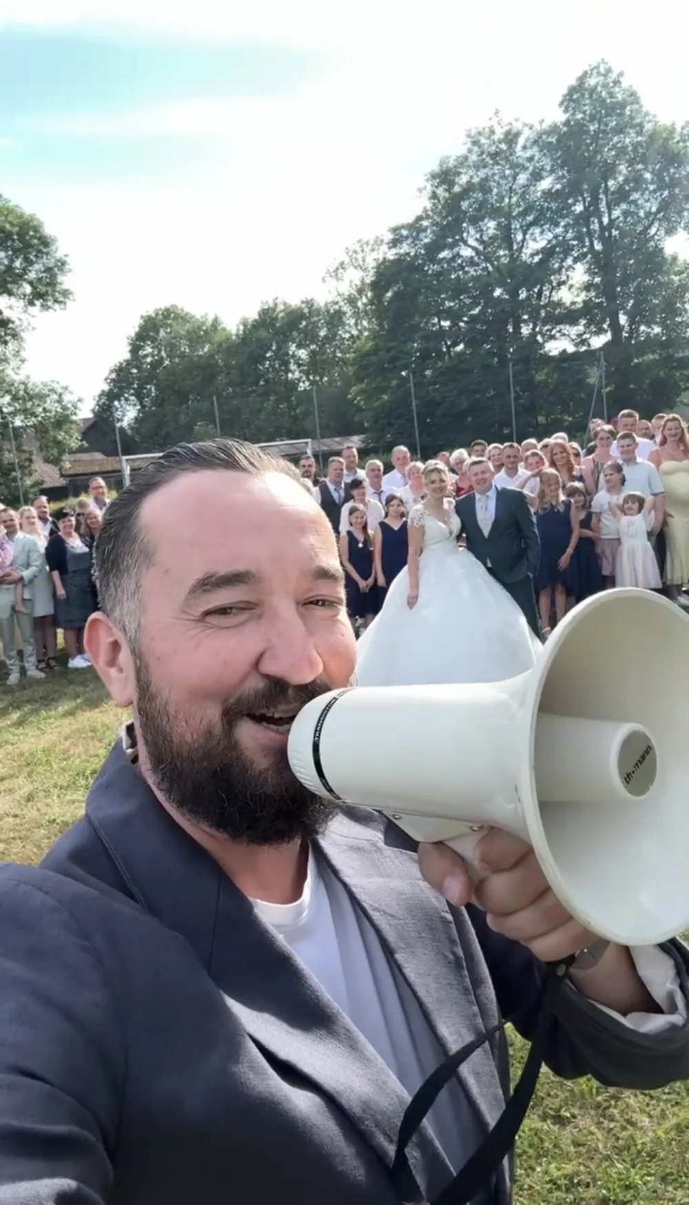 Hochzeitsmoderator Andrey Singer mit Megafon vor den Gästen auf der Wiese Hochzeitsmoderator Andrey Singer mit Megafon vor den Gästen auf der Wiese